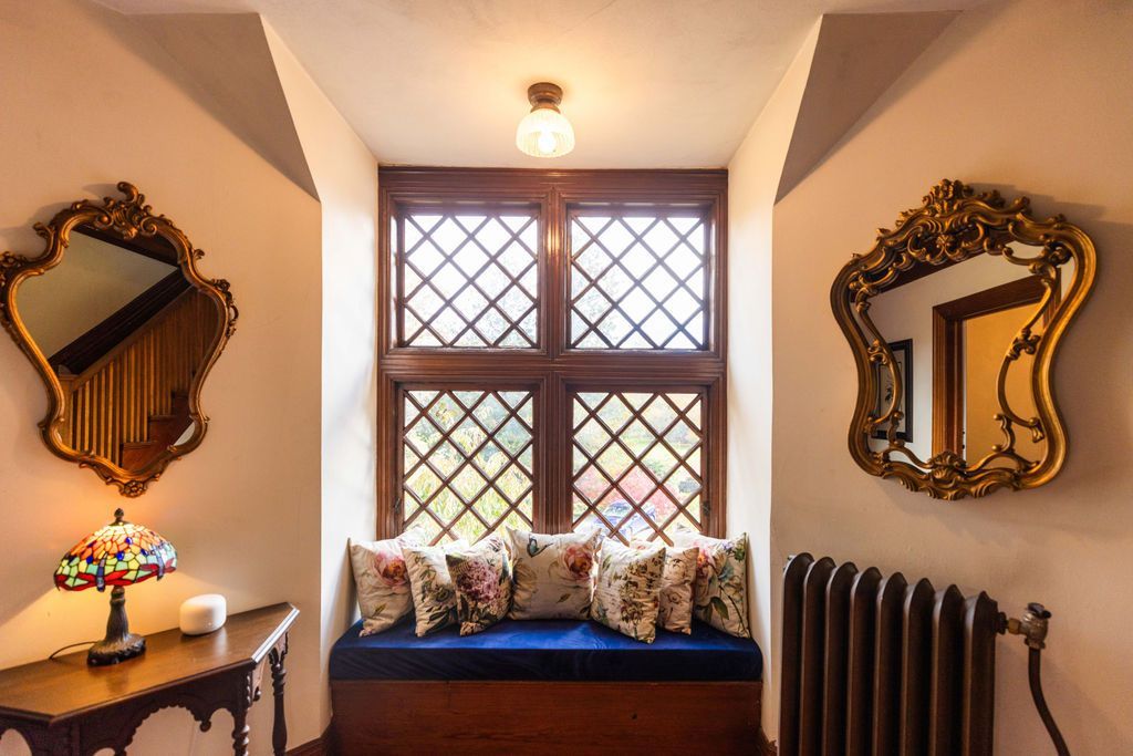 A room with a couch , two mirrors and a radiator.