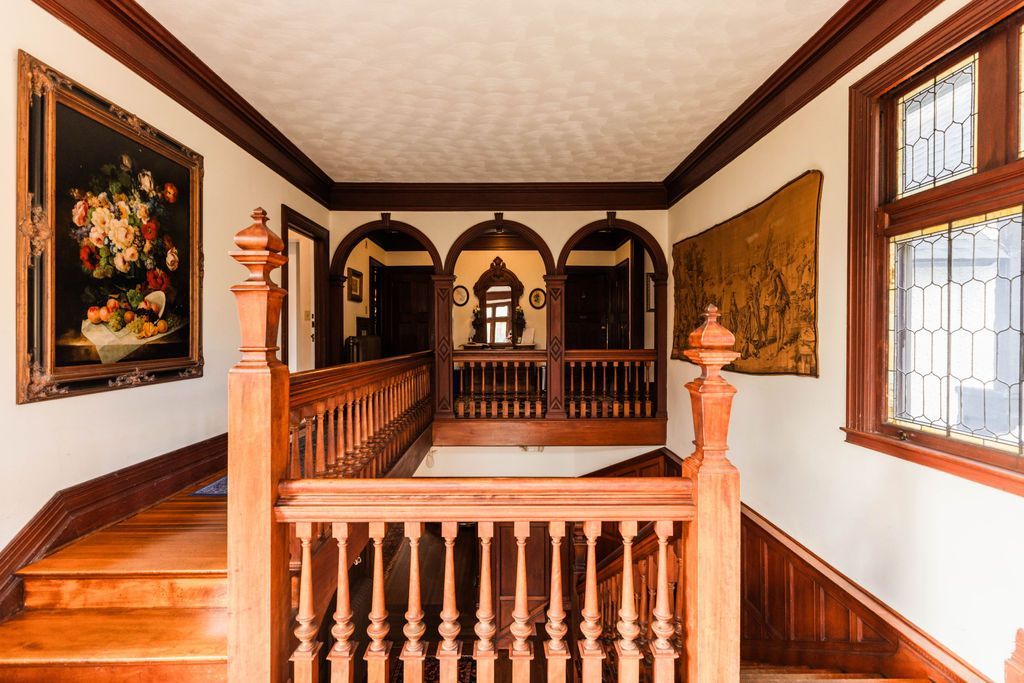 A staircase with a wooden railing and a painting on the wall.
