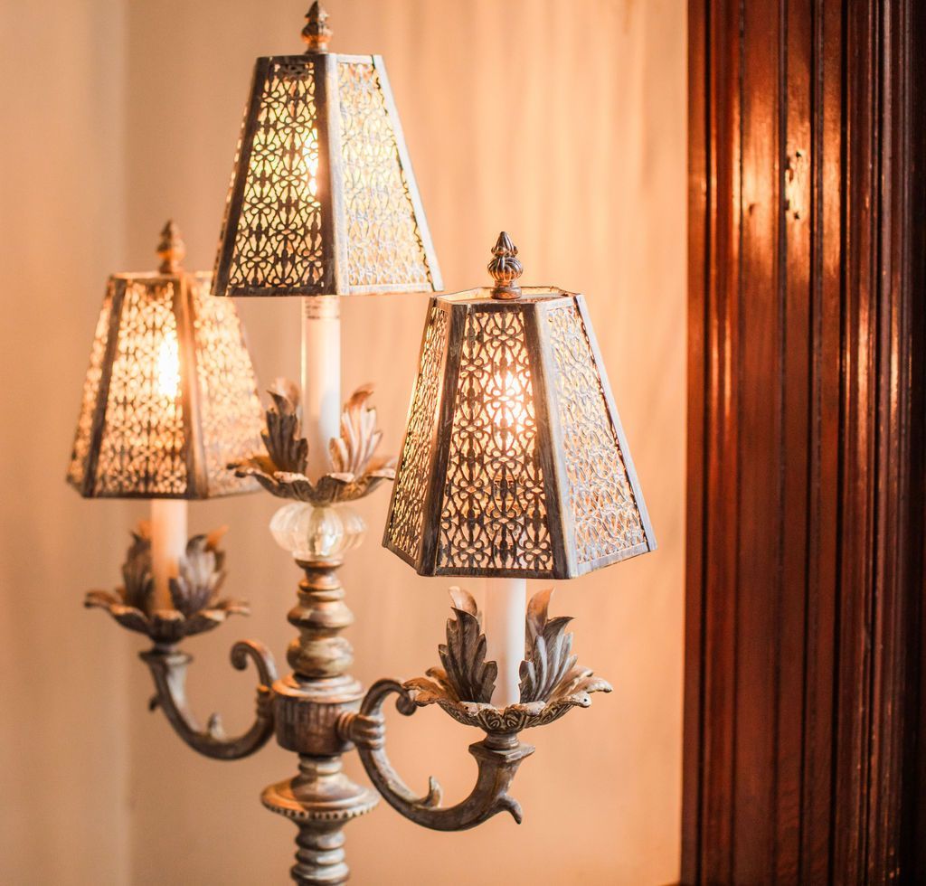 A lamp with three shades is lit up in a room