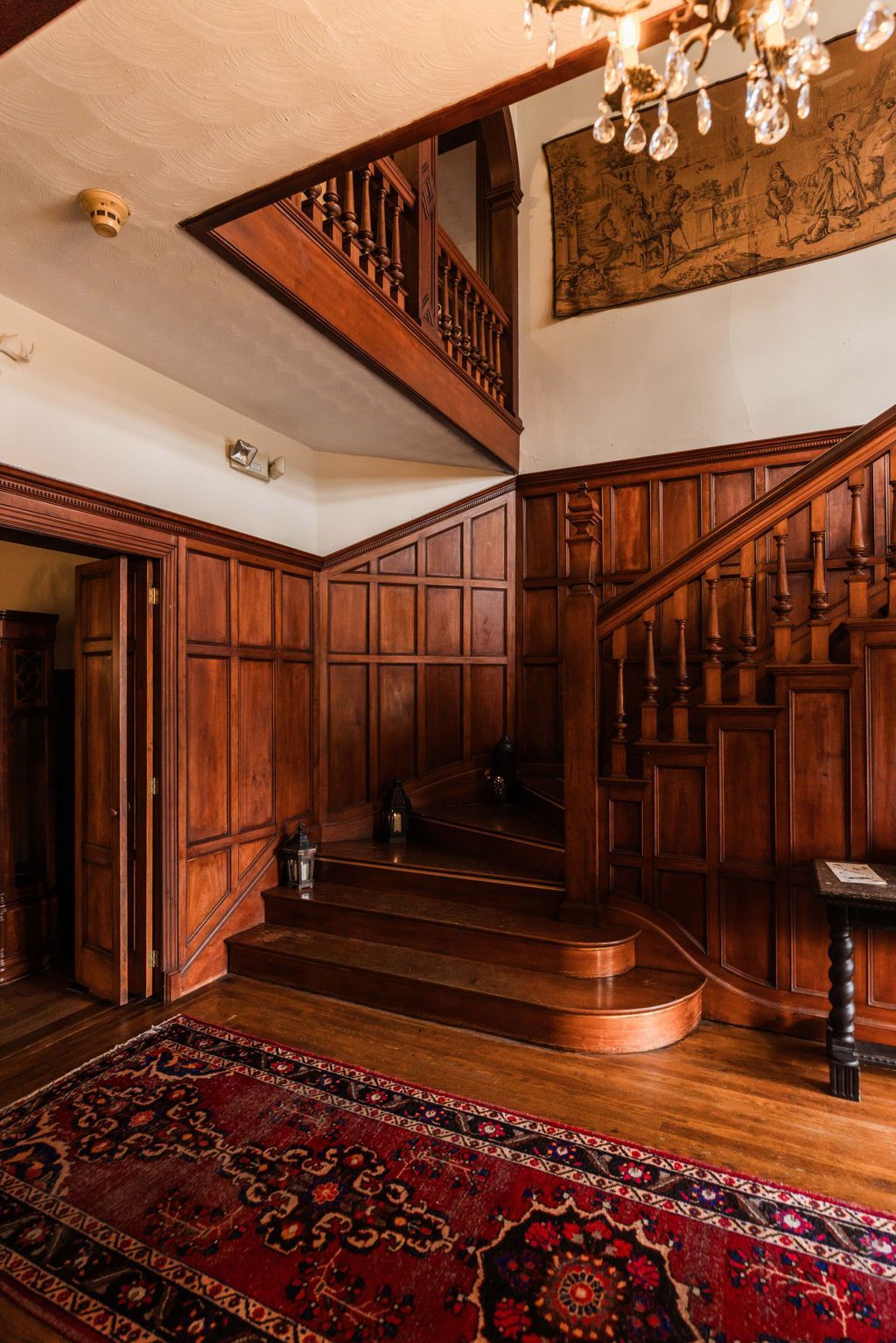A grand staircase with wood-paneled walls ornate bannister.