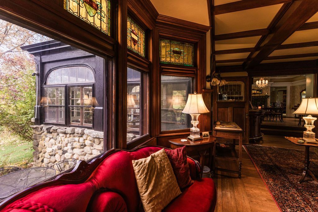 A living room with a red velvet couch, wood paneling, and stained glass windows.