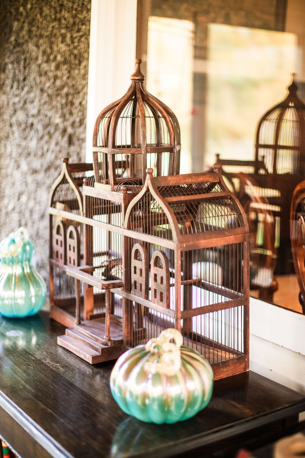 A wooden bird cage is sitting on a table next to a mirror.