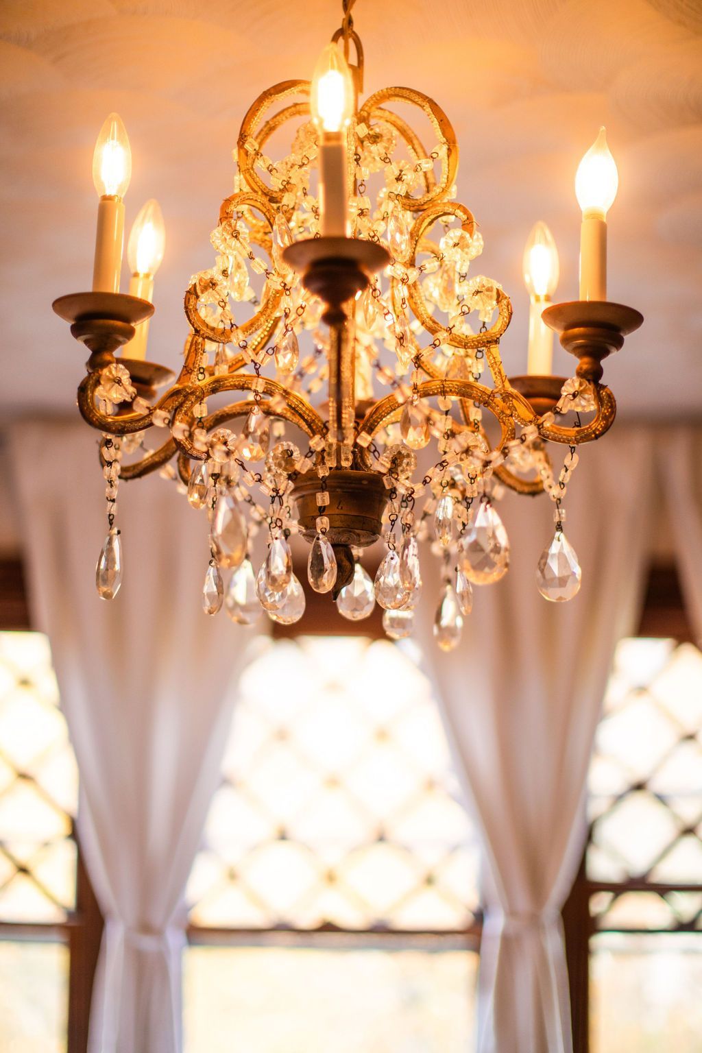 A chandelier is hanging from the ceiling in front of a window.