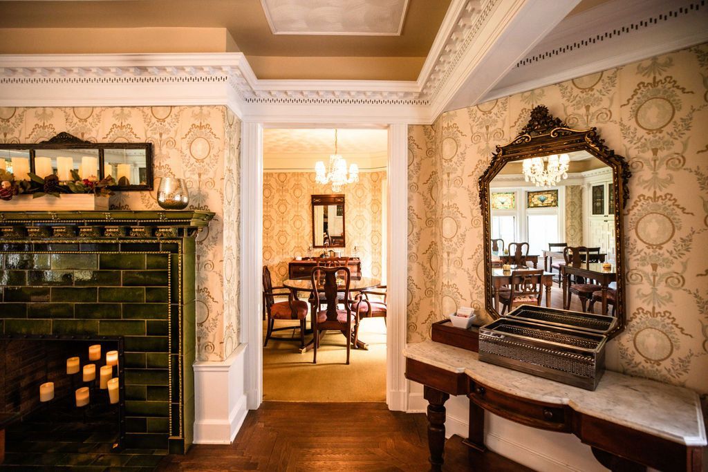A dining room with a fireplace and a mirror.