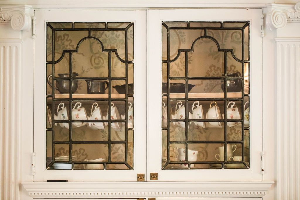 A close-up of a leaded glass curio cabinet with ornate woodwork in a Victorian dining room.