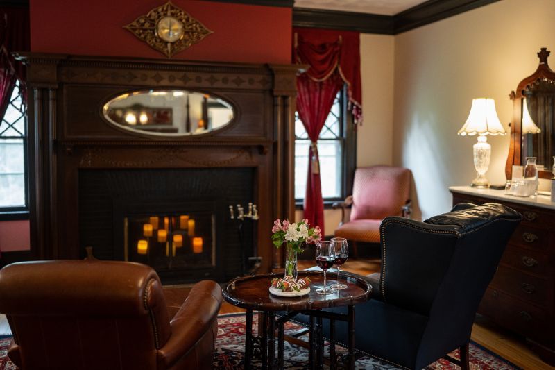 A sitting room at a romantic New England Country Inn with a fireplace, chairs, tables, and lamps.