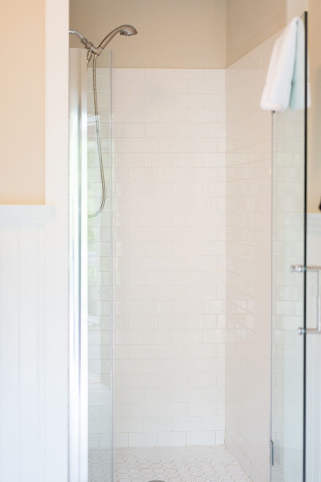 A bathroom with a walk-in shower with a glass door and a shower head.