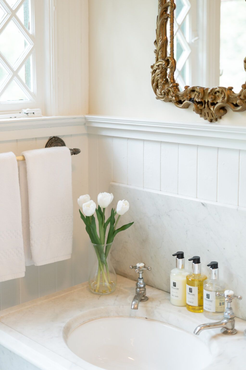 A bathroom sink with a vase of flowers on it and a mirror.
