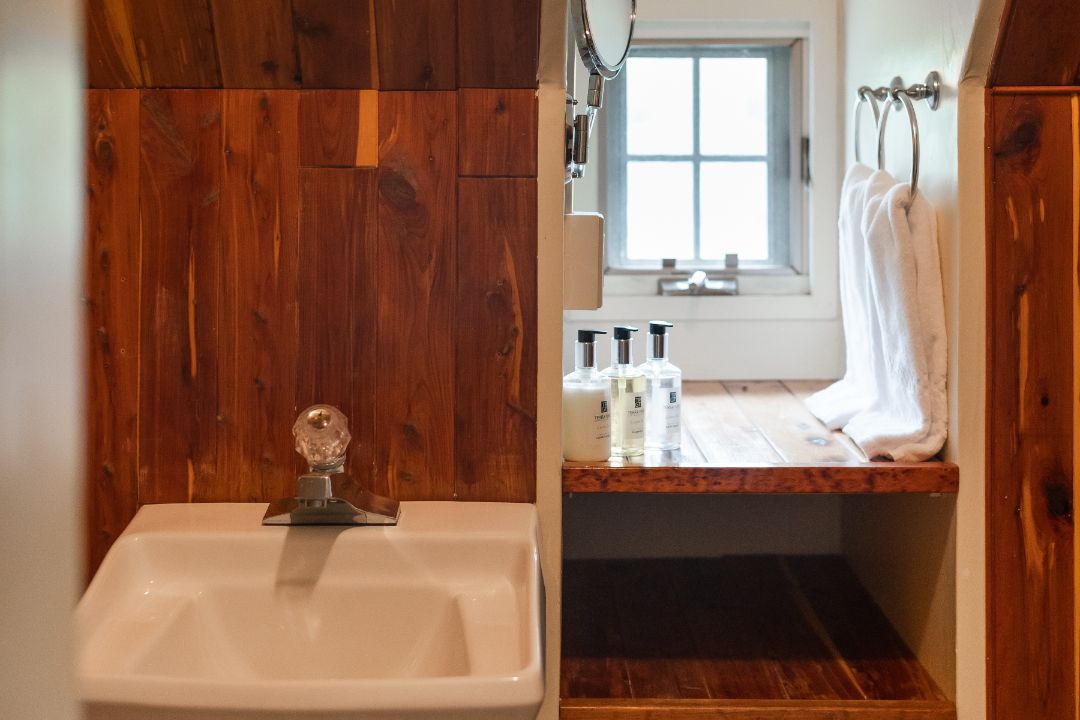 A bathroom with a sink , mirror and window.