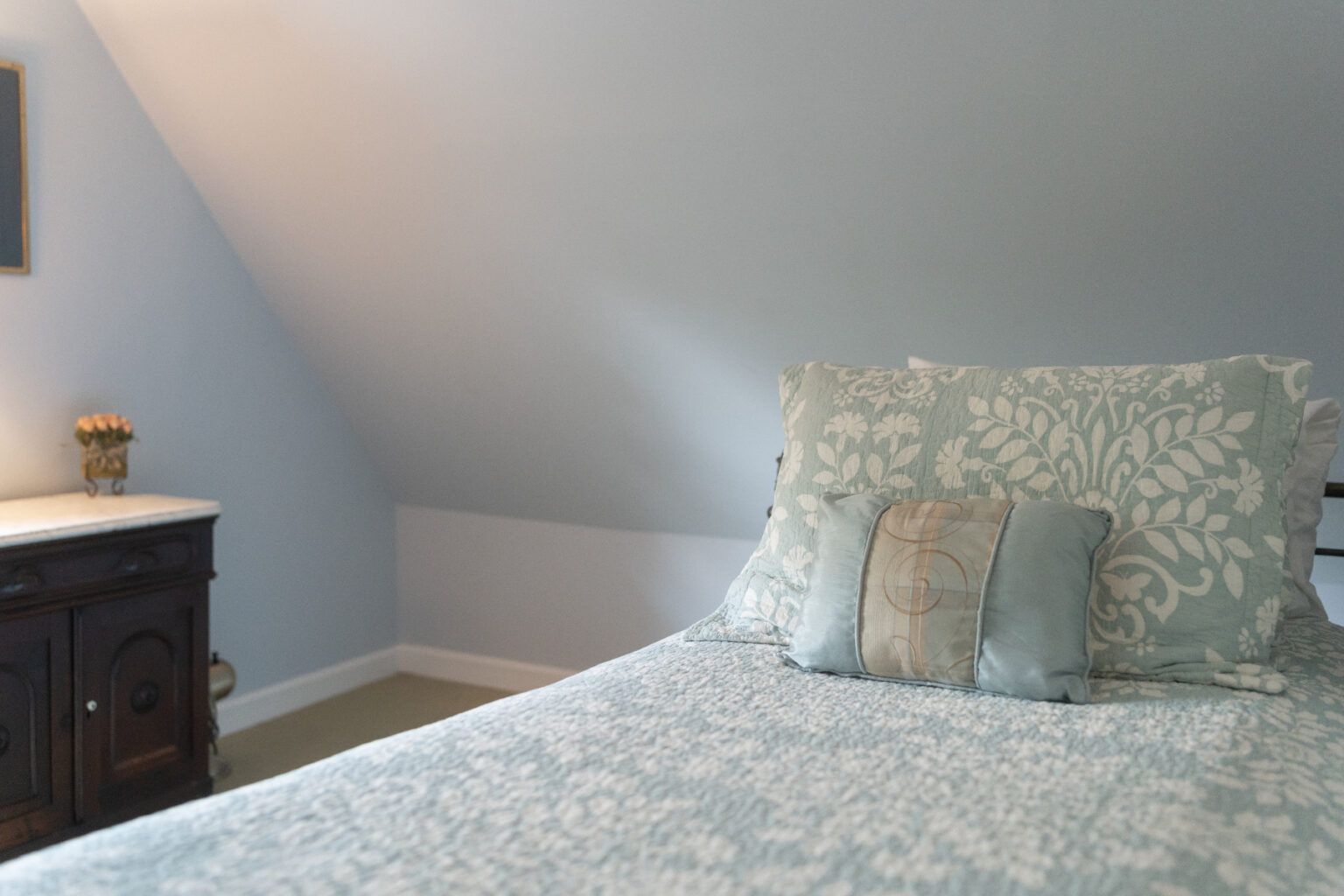 A bedroom with a bed , dresser and nightstand.