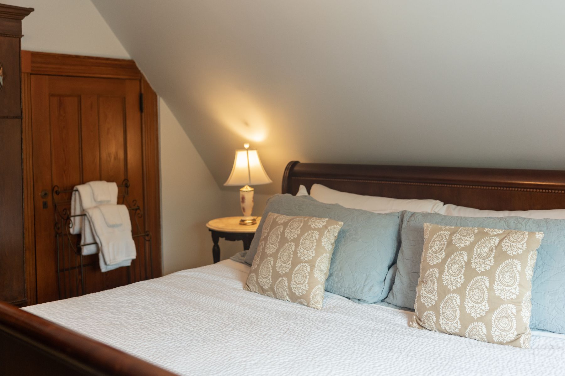 A bedroom with a bed , nightstand and lamp.
