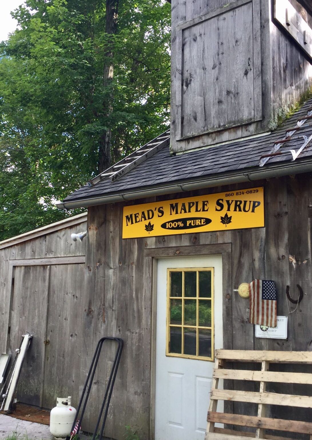 A wooden building with a yellow sign that says mead 's maple syrup