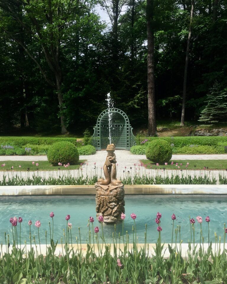 A fountain in a garden with trees in the background