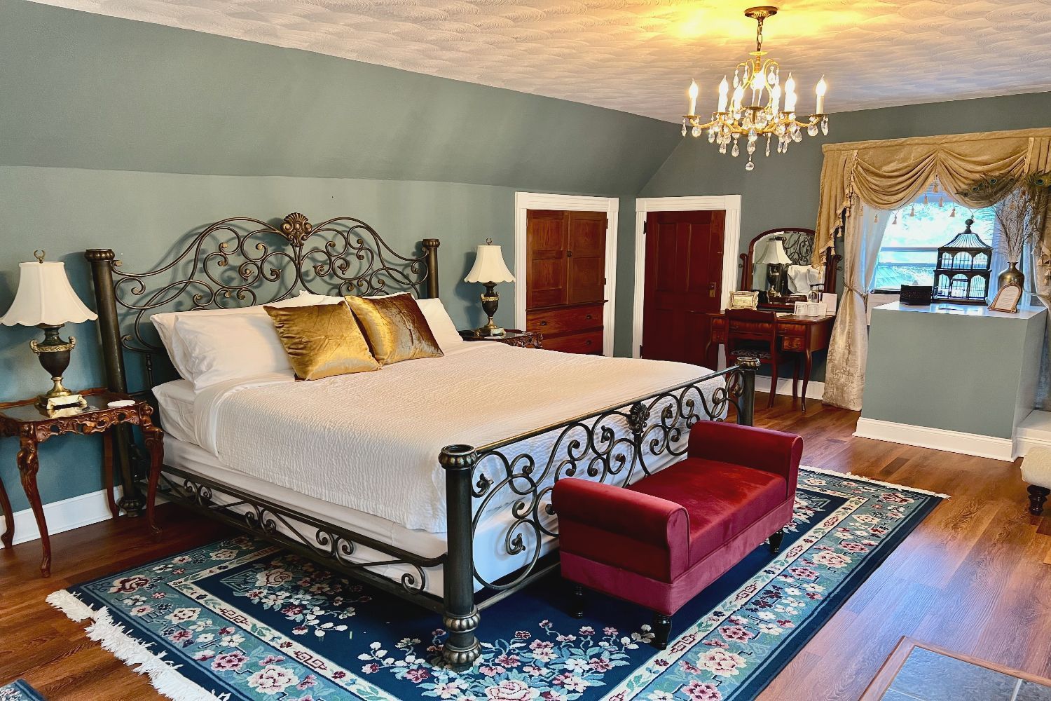 A Victorian-style bedroom with vintage furnishings at a New England Country Inn with a king-size bed and a red velvet bench