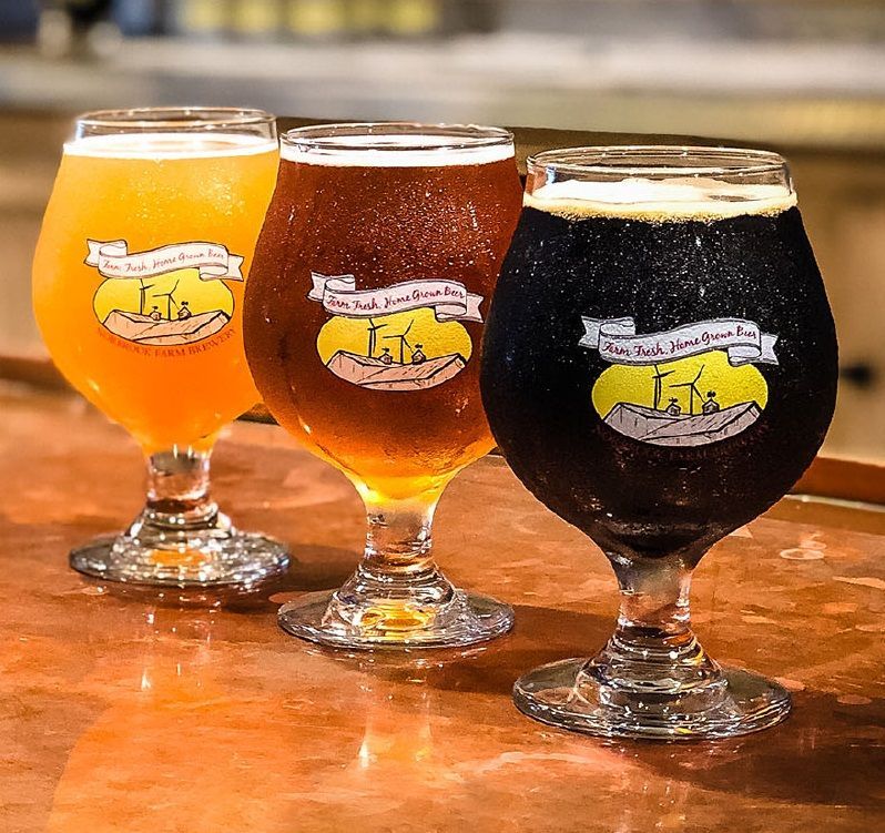 Three glasses of beer are sitting on a table.