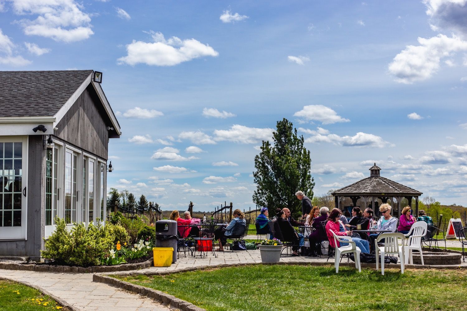 A group of people are sitting at tables outside of a building.