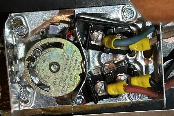 An open furnace limit control switch with colored wiring connected to silver terminals on a metal base.