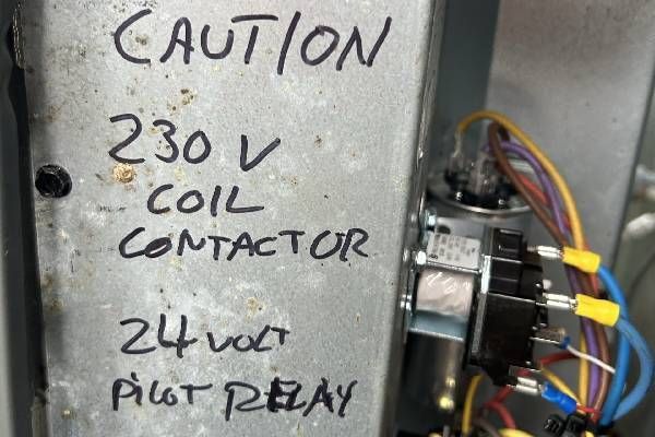 A metal electrical component labeled with handwritten notes indicating a 230V coil contactor and a 24V pilot relay.