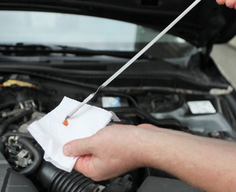 Technician checking the oil level of a car