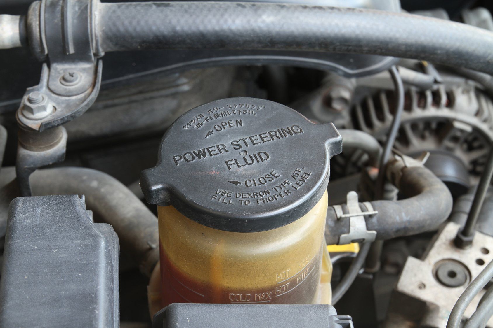 A close up of a power steering fluid container in a car engine