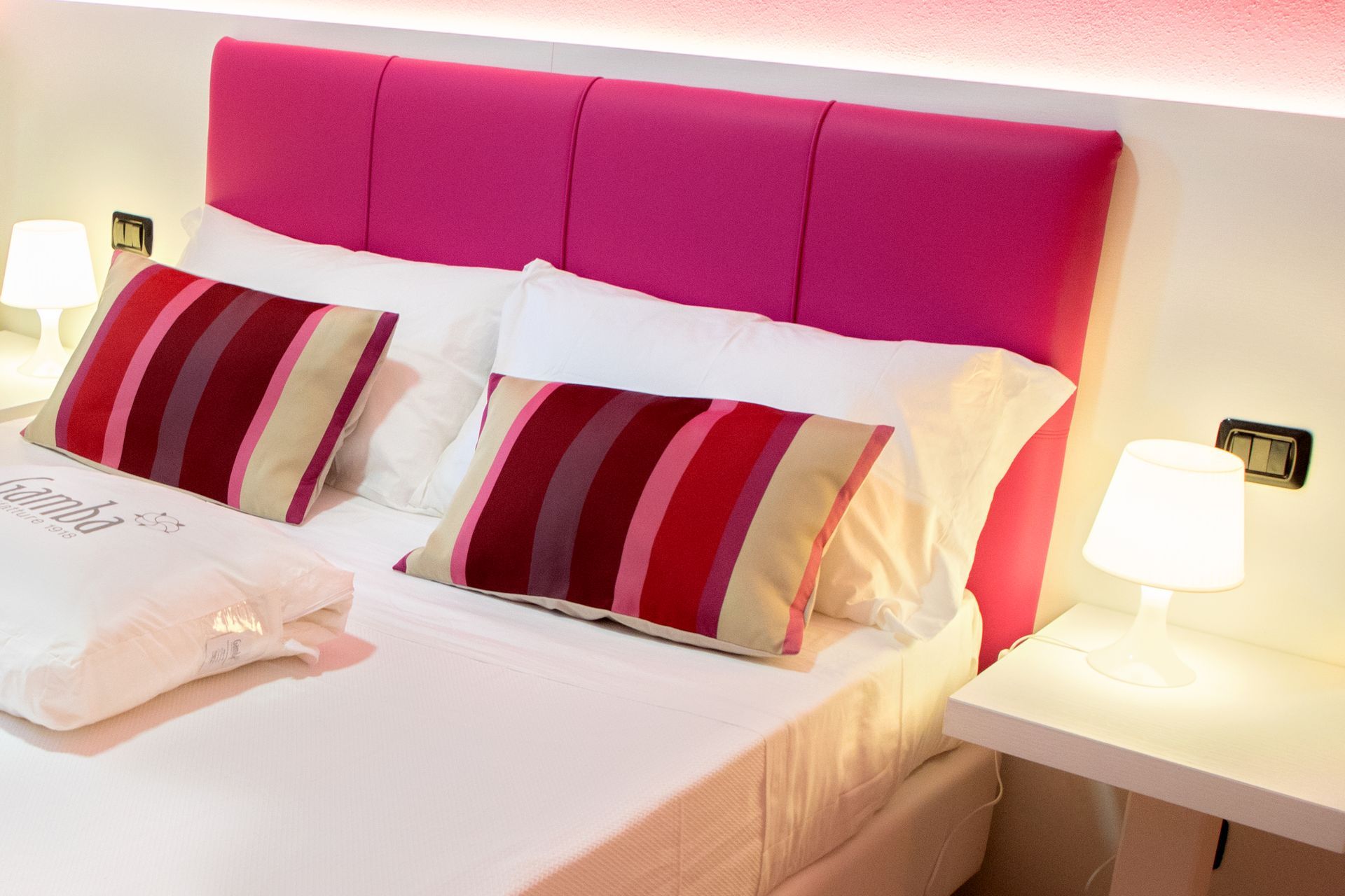 Un letto con testiera rosa e cuscini a righe