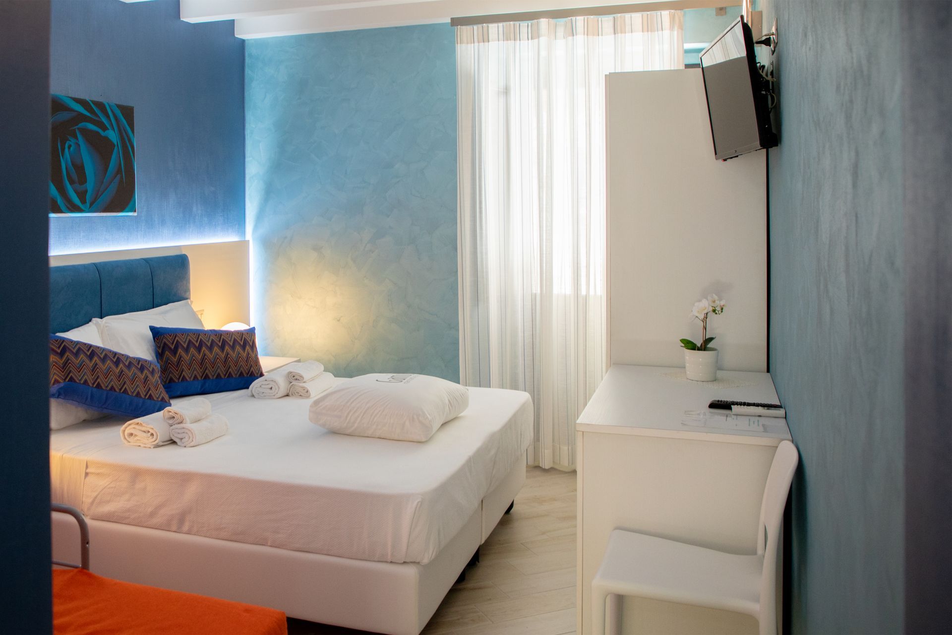 Una stanza d'albergo con un letto, una scrivania, una sedia e una televisione.