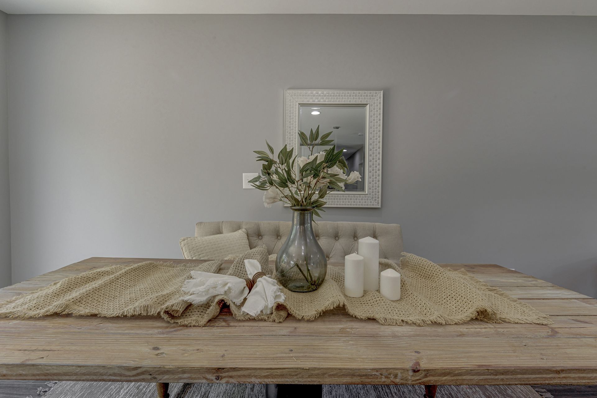 A dining room table with a vase of flowers and candles on it.