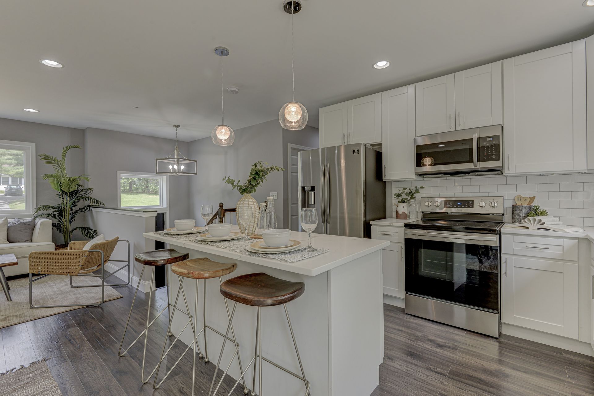 A kitchen with white cabinets , stainless steel appliances , and a large island.