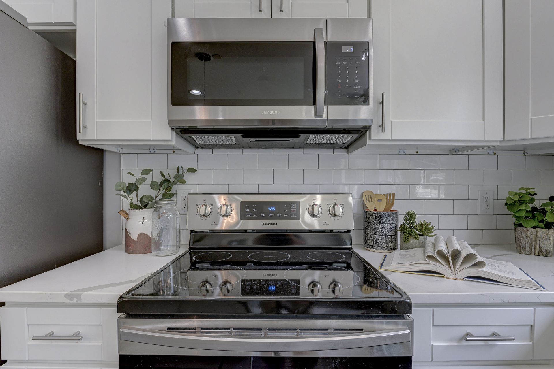 A kitchen with a stove , microwave , and white cabinets.