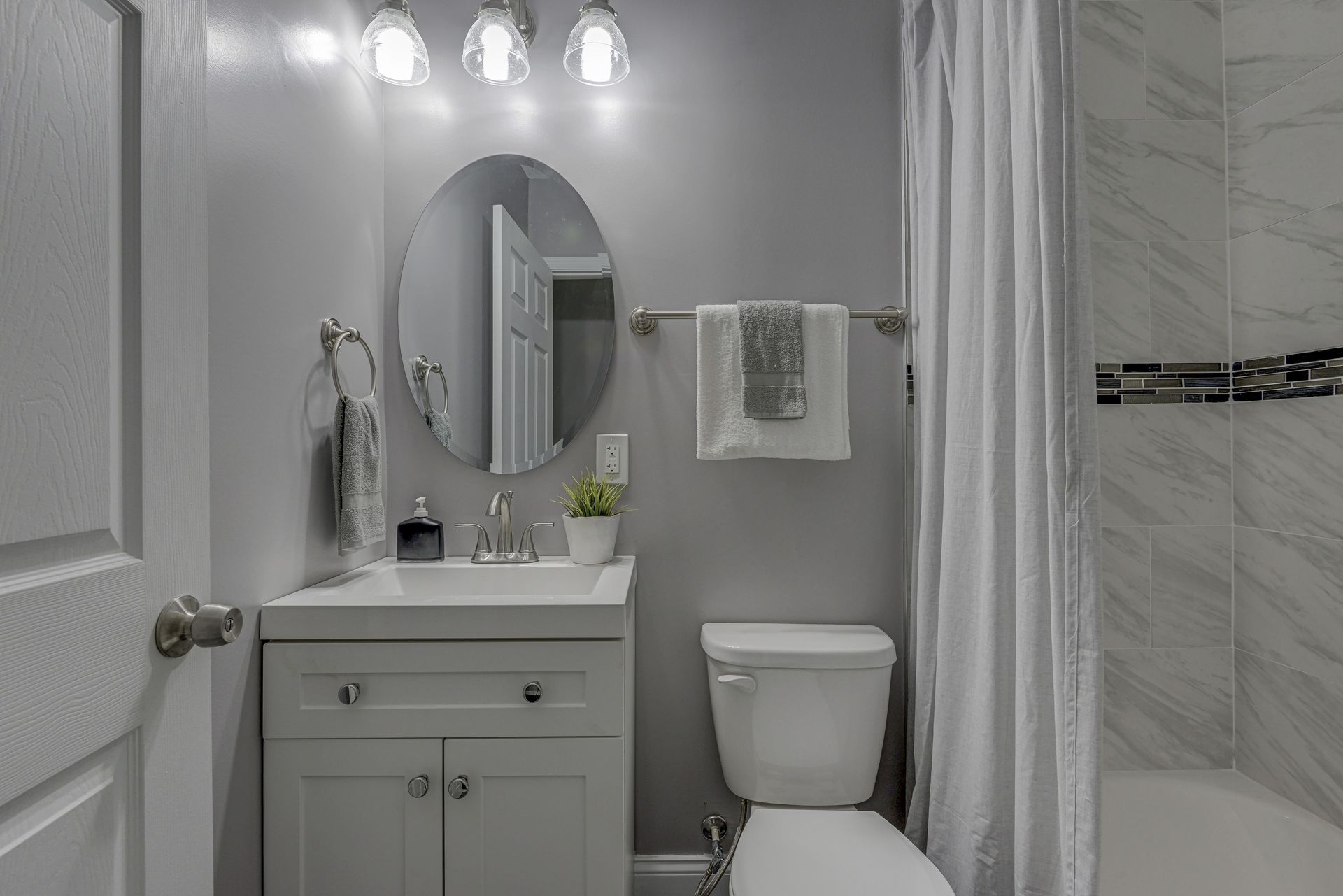 A bathroom with a toilet , sink , mirror and shower curtain.
