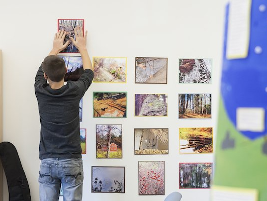 A youngster is hanging a picture on a wall.