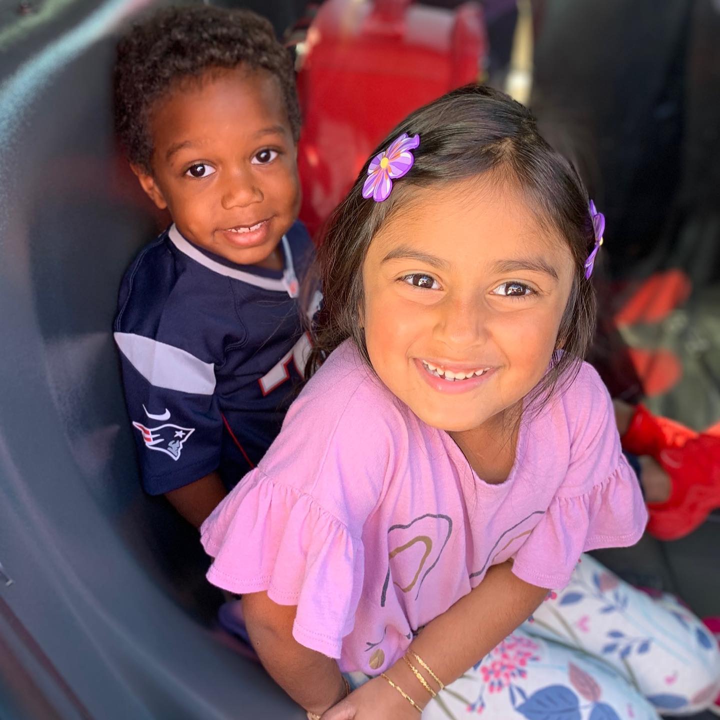 A boy in a patriots jersey sits next to a girl in a pink shirt