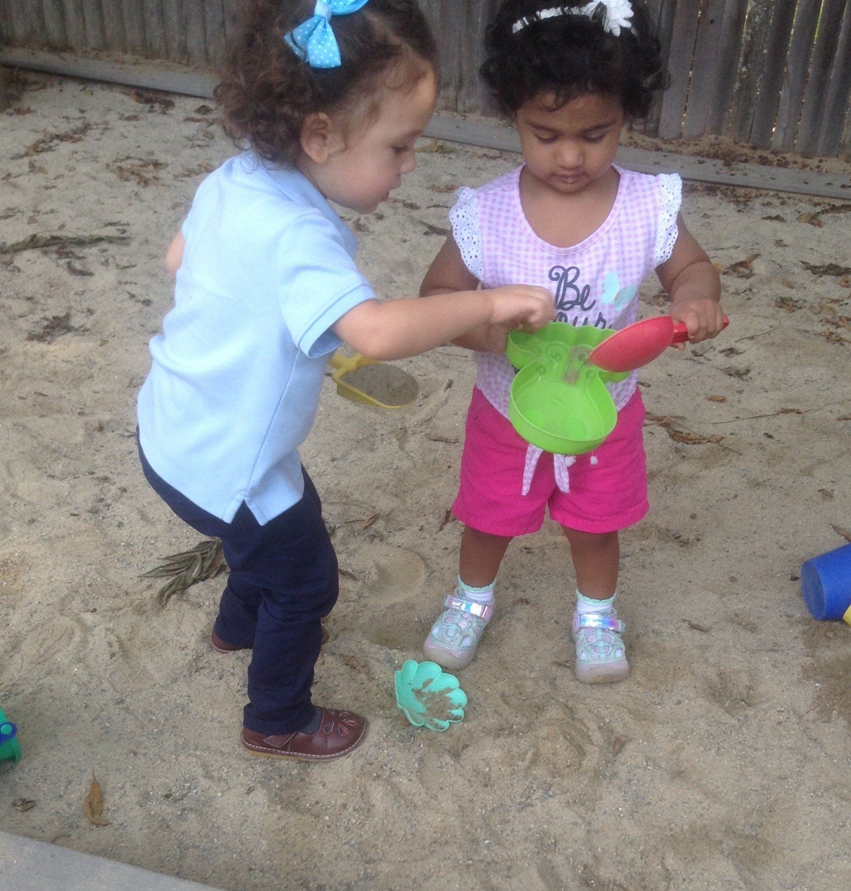 Two little girls are playing in the sand 