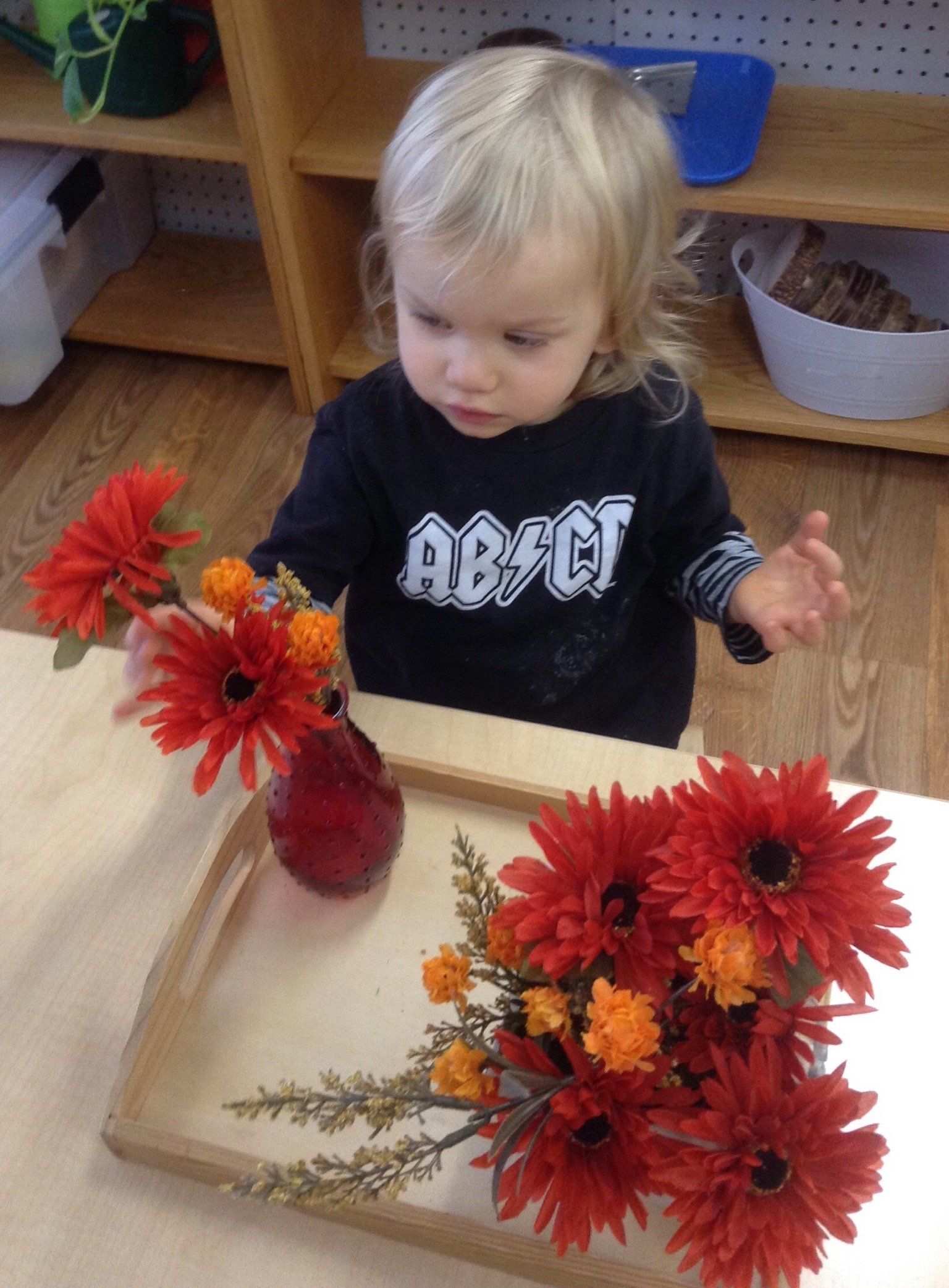 A young boy wearing a shirt is making flower arrangements.