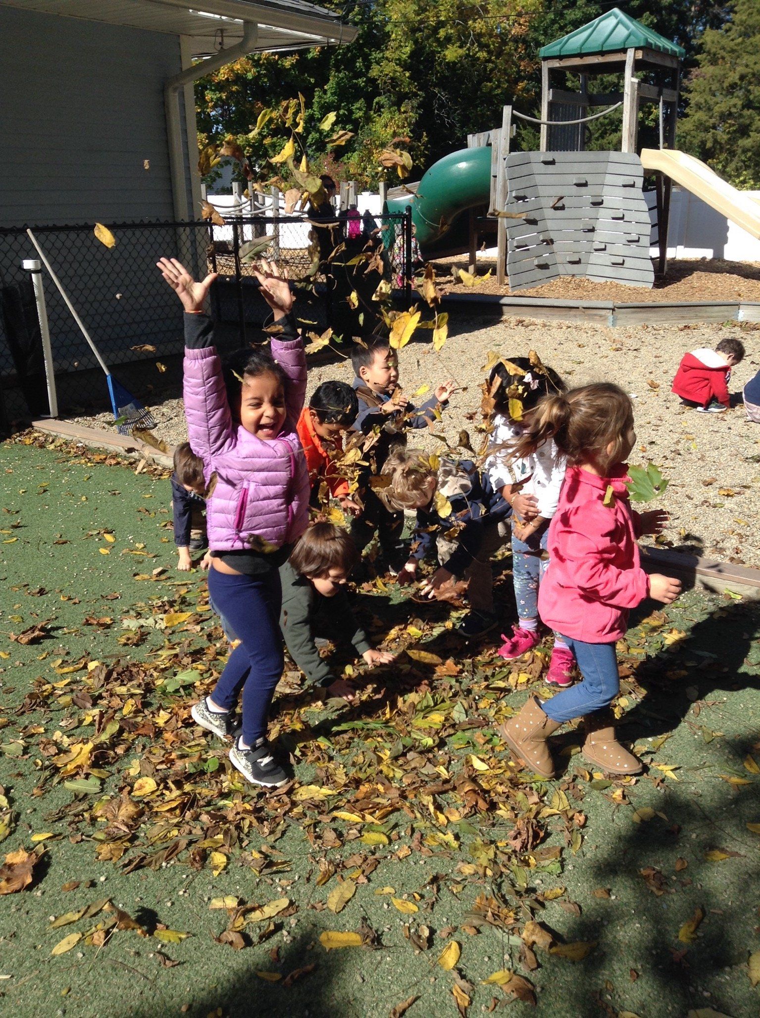 A group of children are playing with leaves in a playground