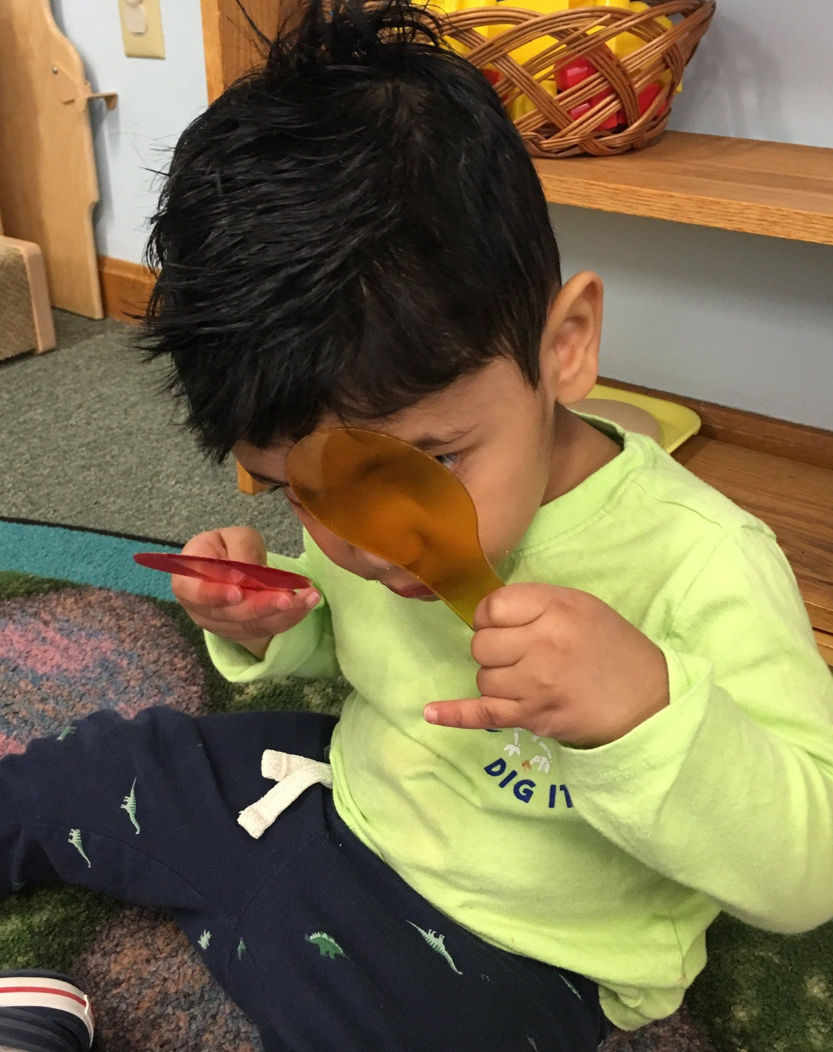 A young boy is sitting on the ground playing with color toys