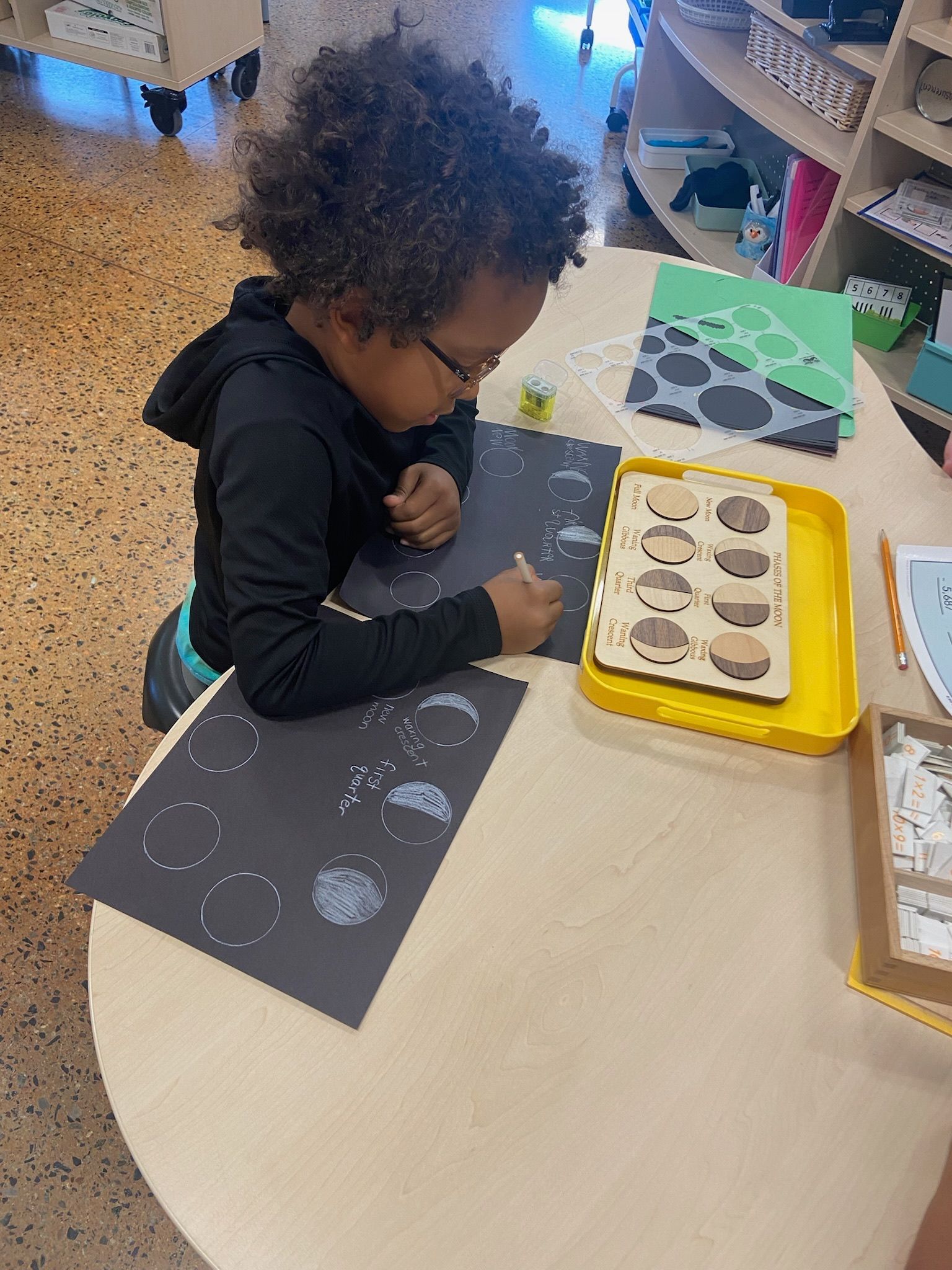 A montessori child is learning about the moon phases working with montessori materials