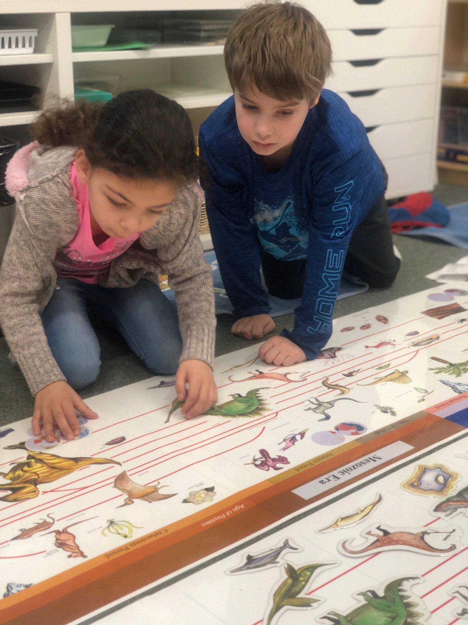 A boy and a girl are looking at a montessori time line