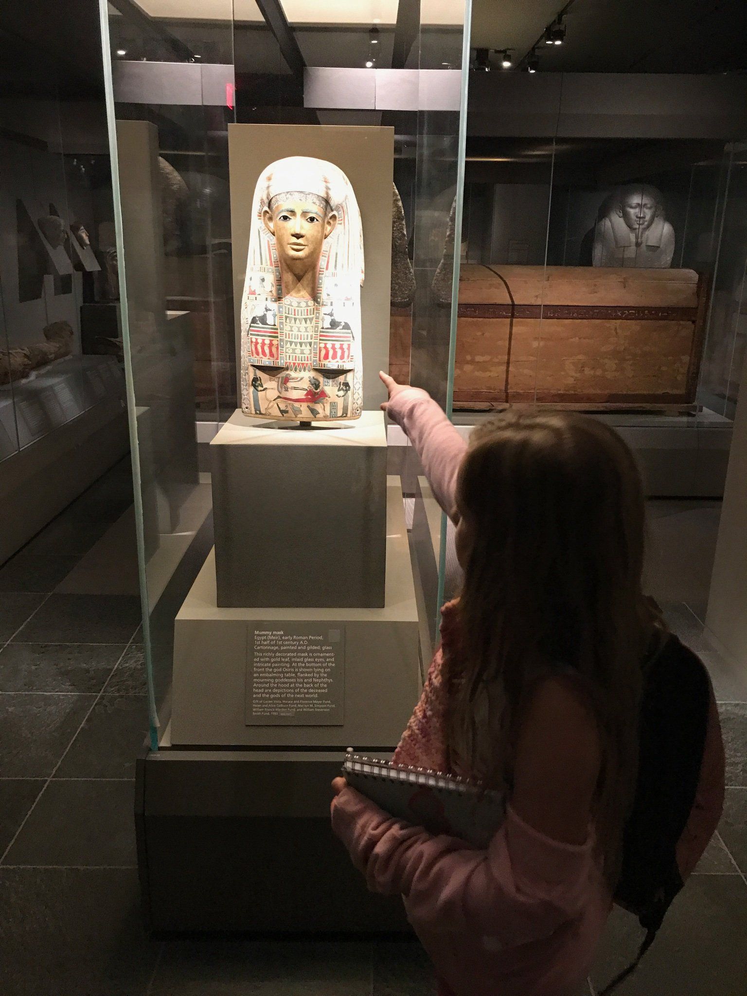 A little girl is pointing at a statue in a museum