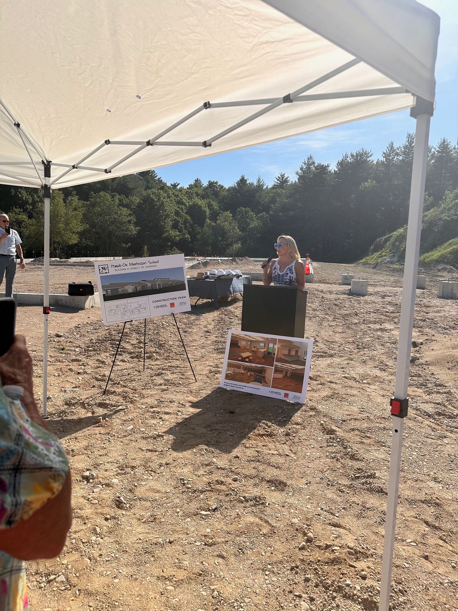 A person is standing under a white tent in a field.