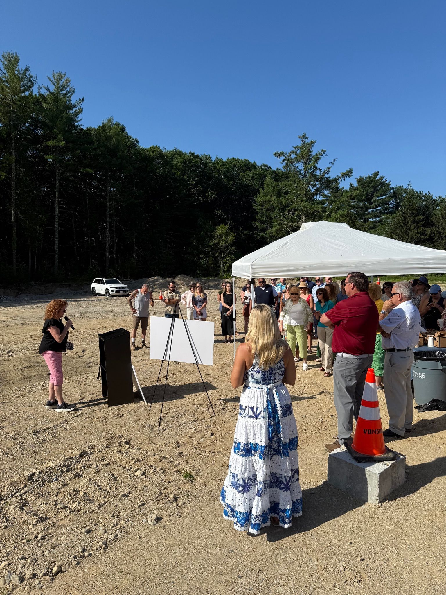 A woman in a blue and white dress is standing in front of a crowd of people.