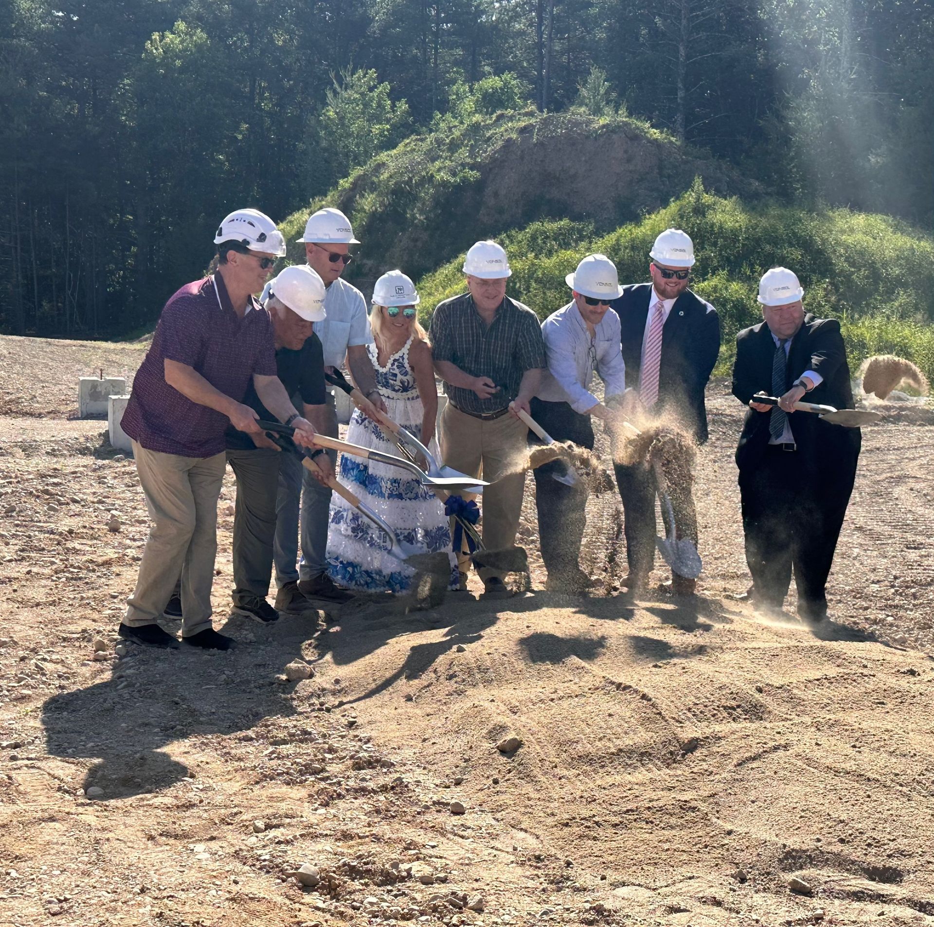 A group of people wearing hard hats are digging in the dirt