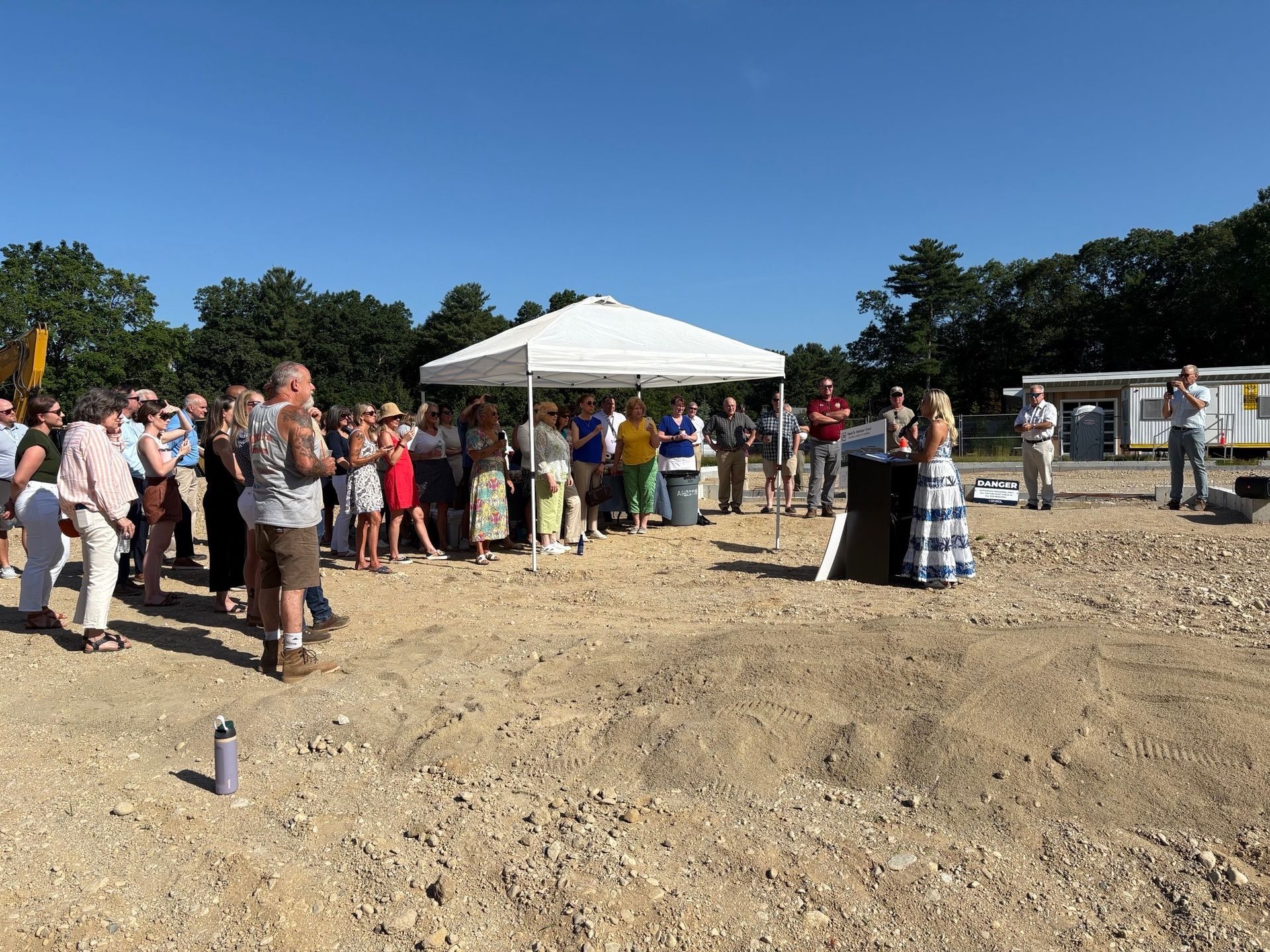 A group of people are standing in a  field under a tent.