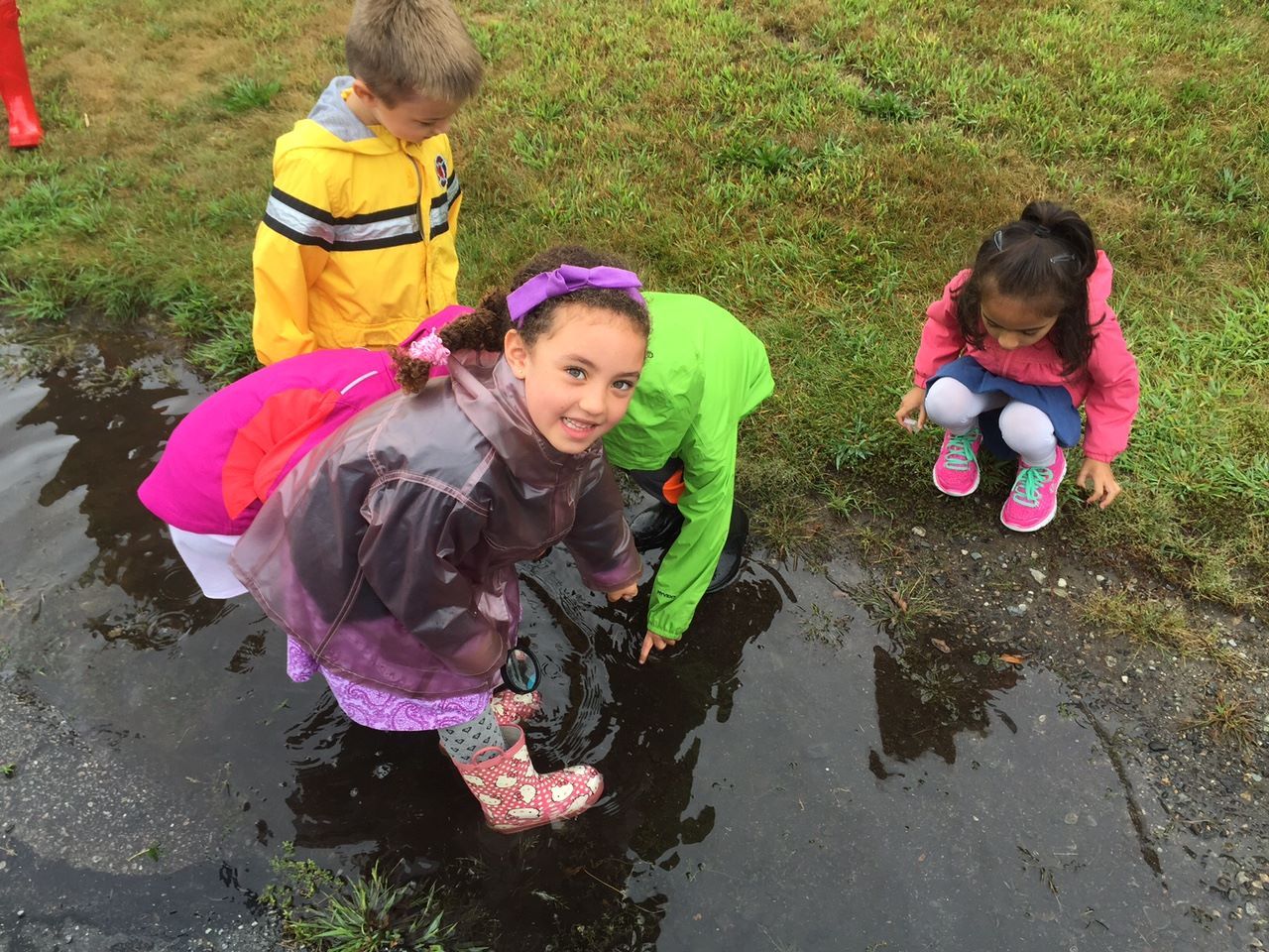 A group of children are playing in a puddle of water.