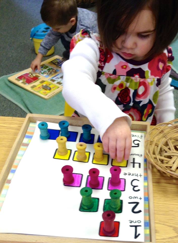 A little girl is playing with math montessori materials