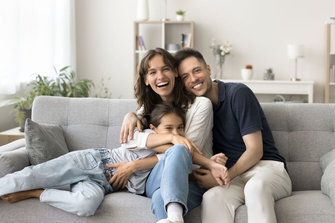 A family is sitting on a couch in a living room.