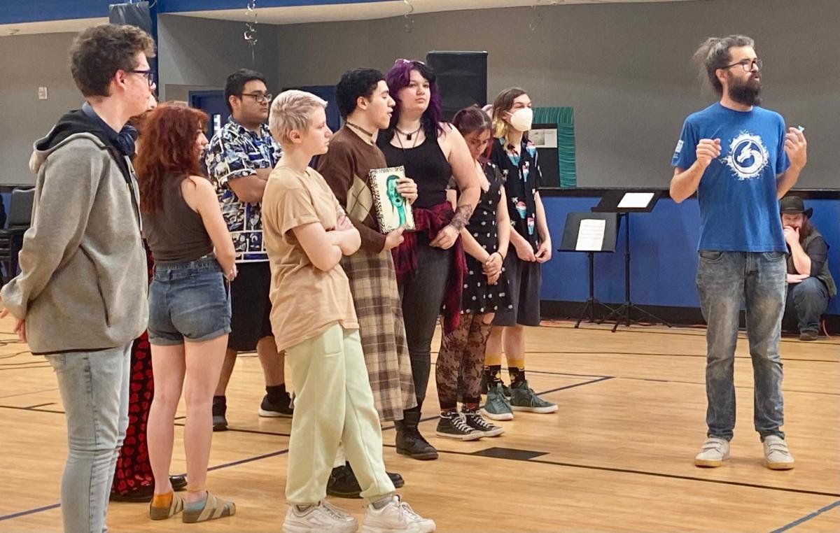 A man in a blue shirt with the number 3 on it is standing in front of a group of people.