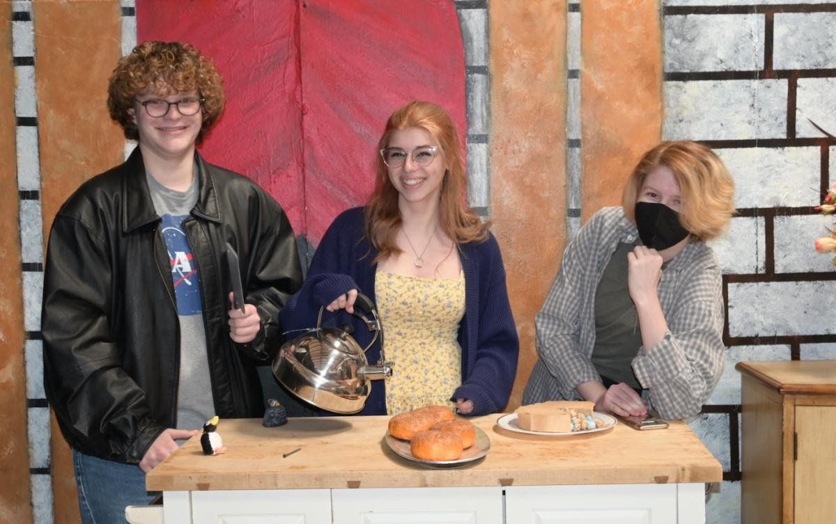Three people are posing for a picture in front of a kitchen counter.