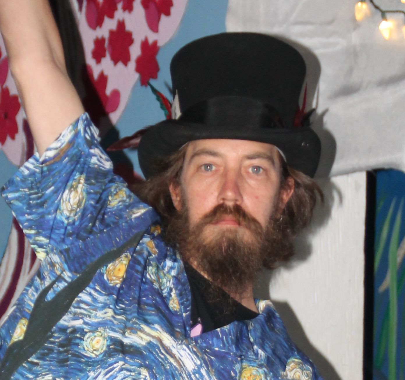 A man with a beard wearing a top hat and a starry night shirt