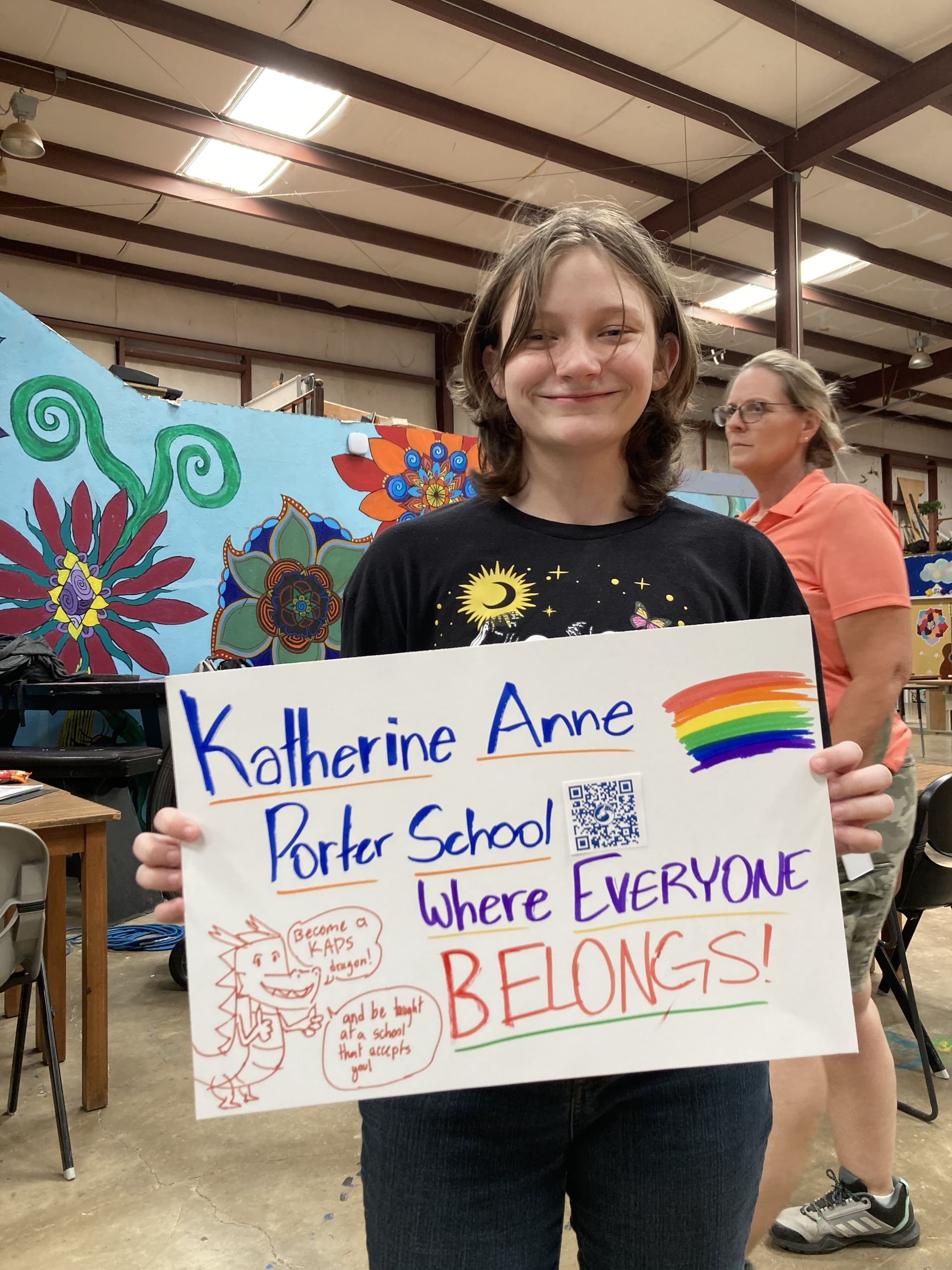 Hallie, holding a 'Where Everyone Belongs' poster.